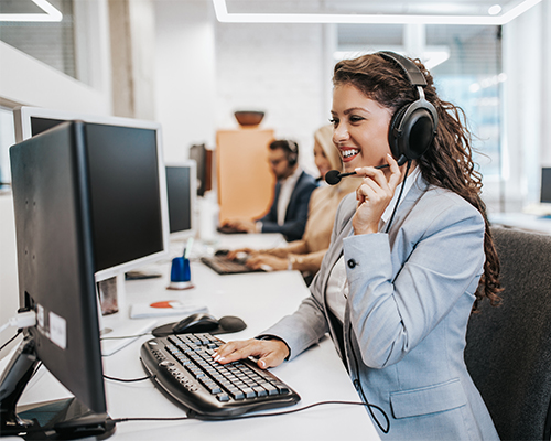 Beautiful smiling female call center worker accompanied by her team working in the office.